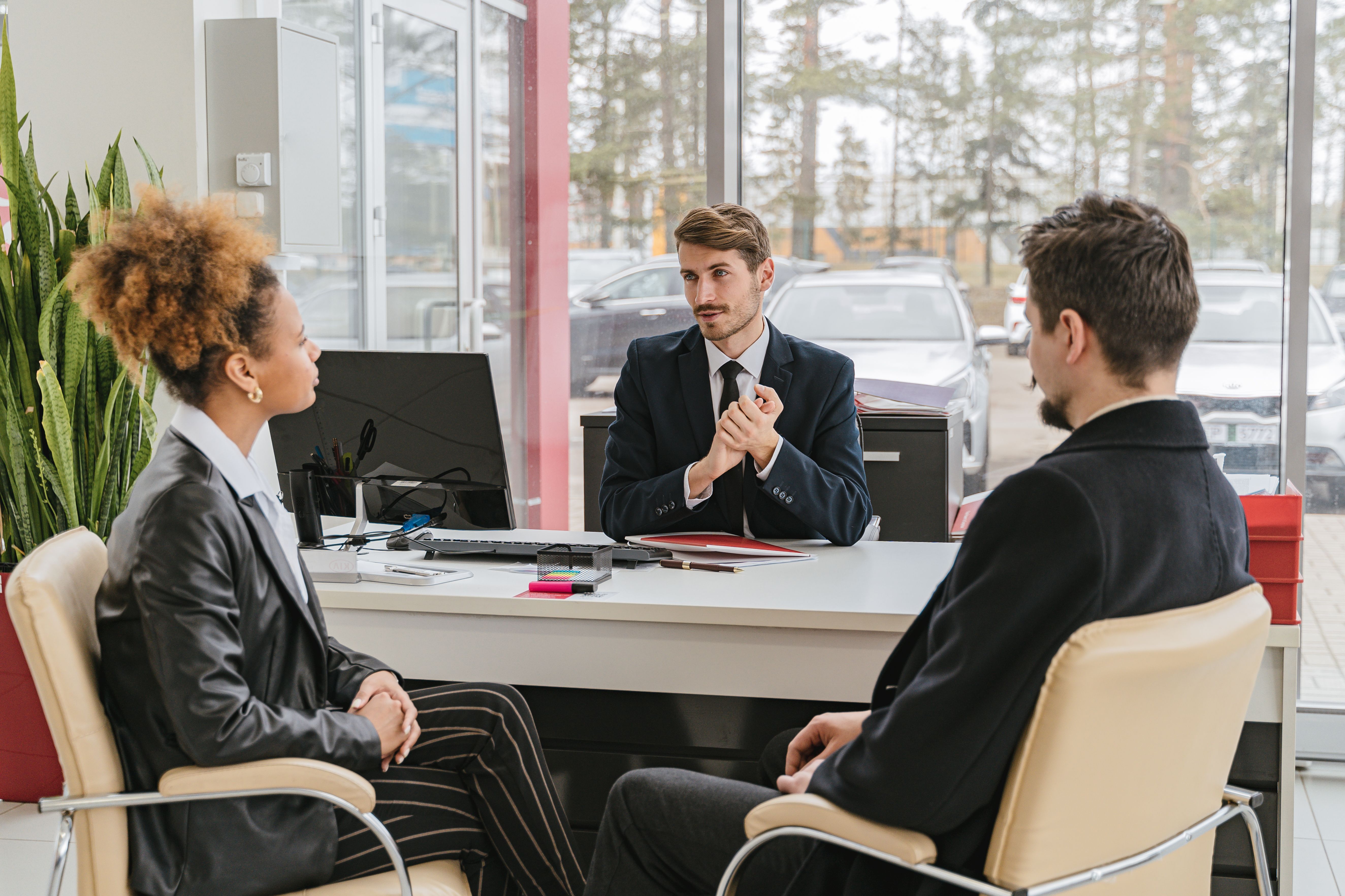 Sales manager handing a box to a customer beside their new car